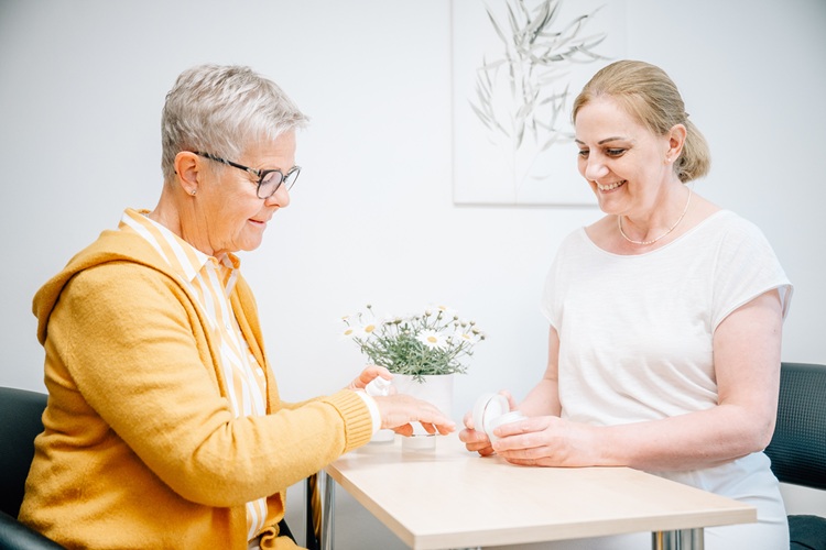 Heike Weigand zeigt einer Kundin eine Pflegecreme 