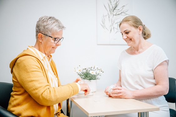 Heike Weigand zeigt eine Kundin eine Pflegecreme, welche die Kundin auf dem Handr&uuml;cken ausprobiert