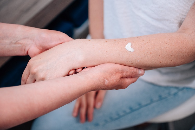 Heike Weigand hät den Arm einer Kundin mit einem Herz aus Creme auf dem Arn