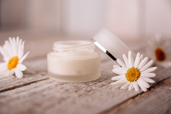 Offener Tiegel mit Creme und Bl&uuml;ten