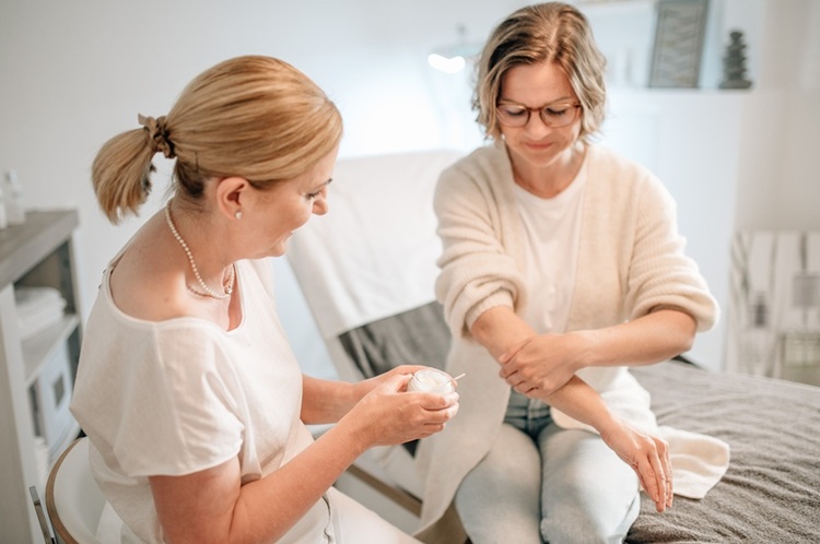 Heike Weigand zeigt einer Kundin eine Pflegecreme, die sich die Kundin auf den Arm aufträgt